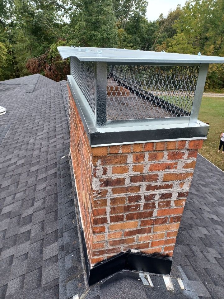 Brick chimney with a metal cap on a shingled roof.