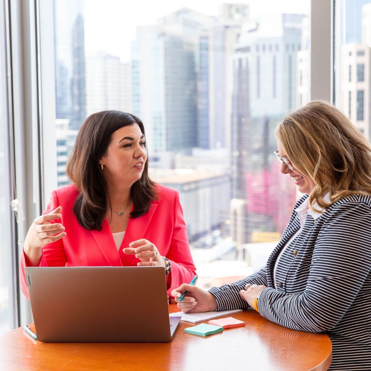 Two women are sitting at a table with a laptop.