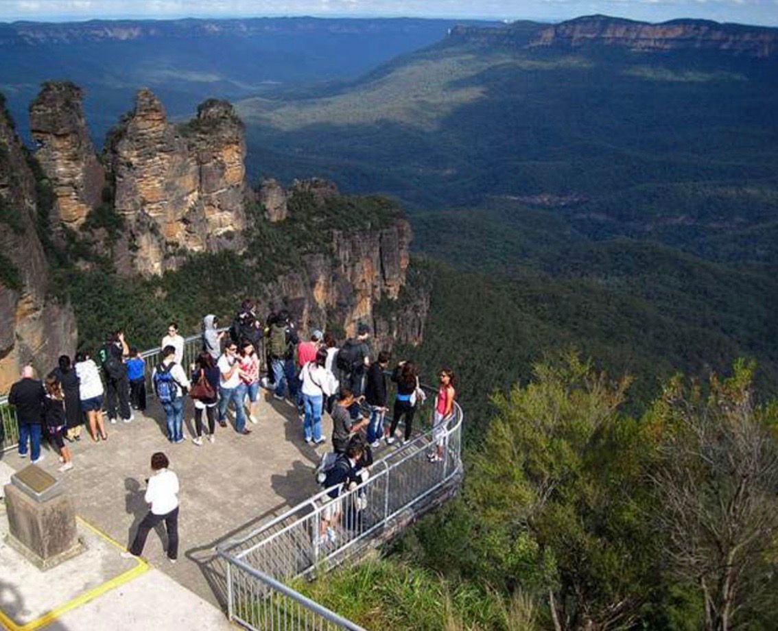 Echo Point Lookout is a popular tourist destination in Katoomba, Australia. It offers panoramic views of the Jamison Valley and the Three Sisters, a group of three sandstone rock formations. The Three Sisters are a UNESCO World Heritage Site and one of the most iconic landmarks in Australia.  The image shows a view of Echo Point Lookout from the Jamison Valley. The Three Sisters are visible in the distance, rising up from the valley floor. The lookout is located on the edge of a cliff, and the views from the lookout are breathtaking. On a clear day, you can see for miles in every direction.