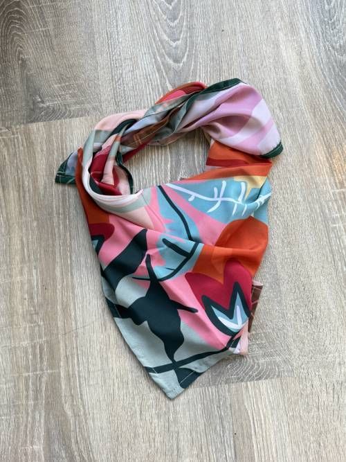 Bufanda infinita con estampado colorido sobre una superficie de madera clara.