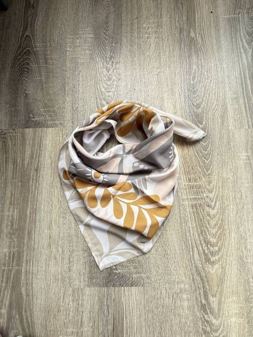 Bufanda infinita estampada en color tostado y mostaza sobre una superficie de madera.