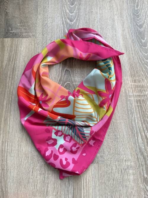 Una colorida bufanda con estampados florales se exhibe sobre una superficie de madera.