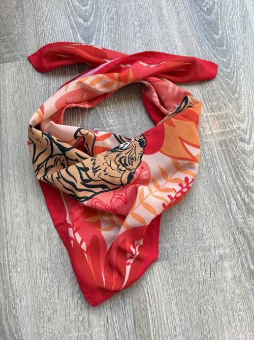 Diadema con estampado floral en color rojo y coral sobre superficie de madera.