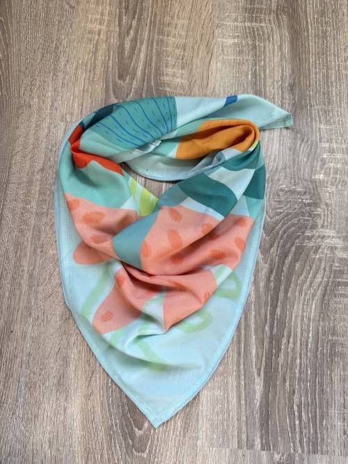 Bufanda colorida con patrones abstractos sobre una superficie de madera.