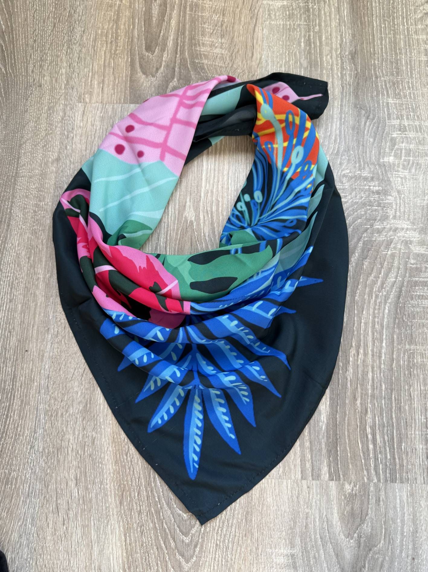 Bufanda infinita negra con estampados florales y geométricos coloridos.