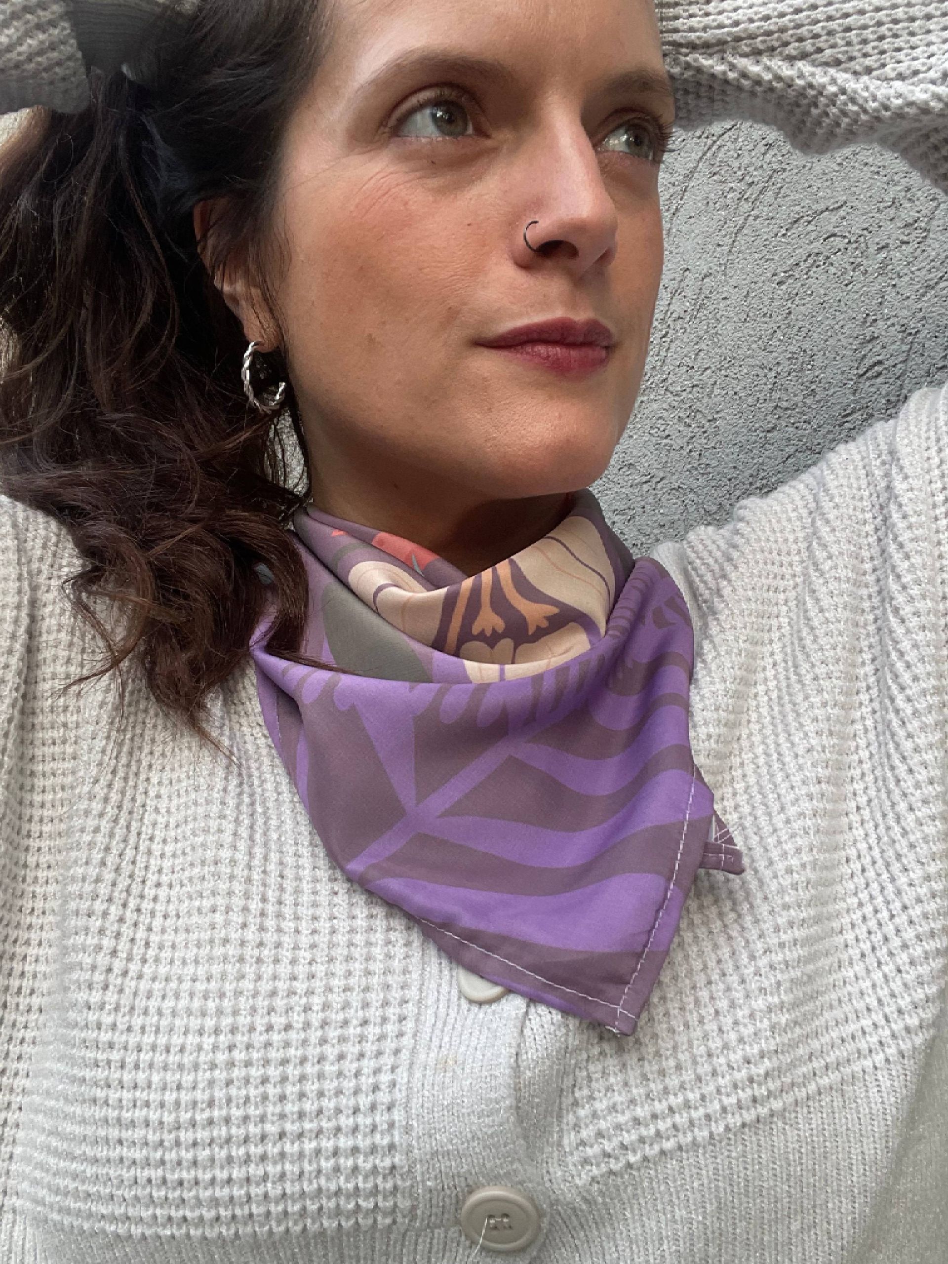 Pañuelo de seda con estampado de color morado y verde azulado atado con un nudo.