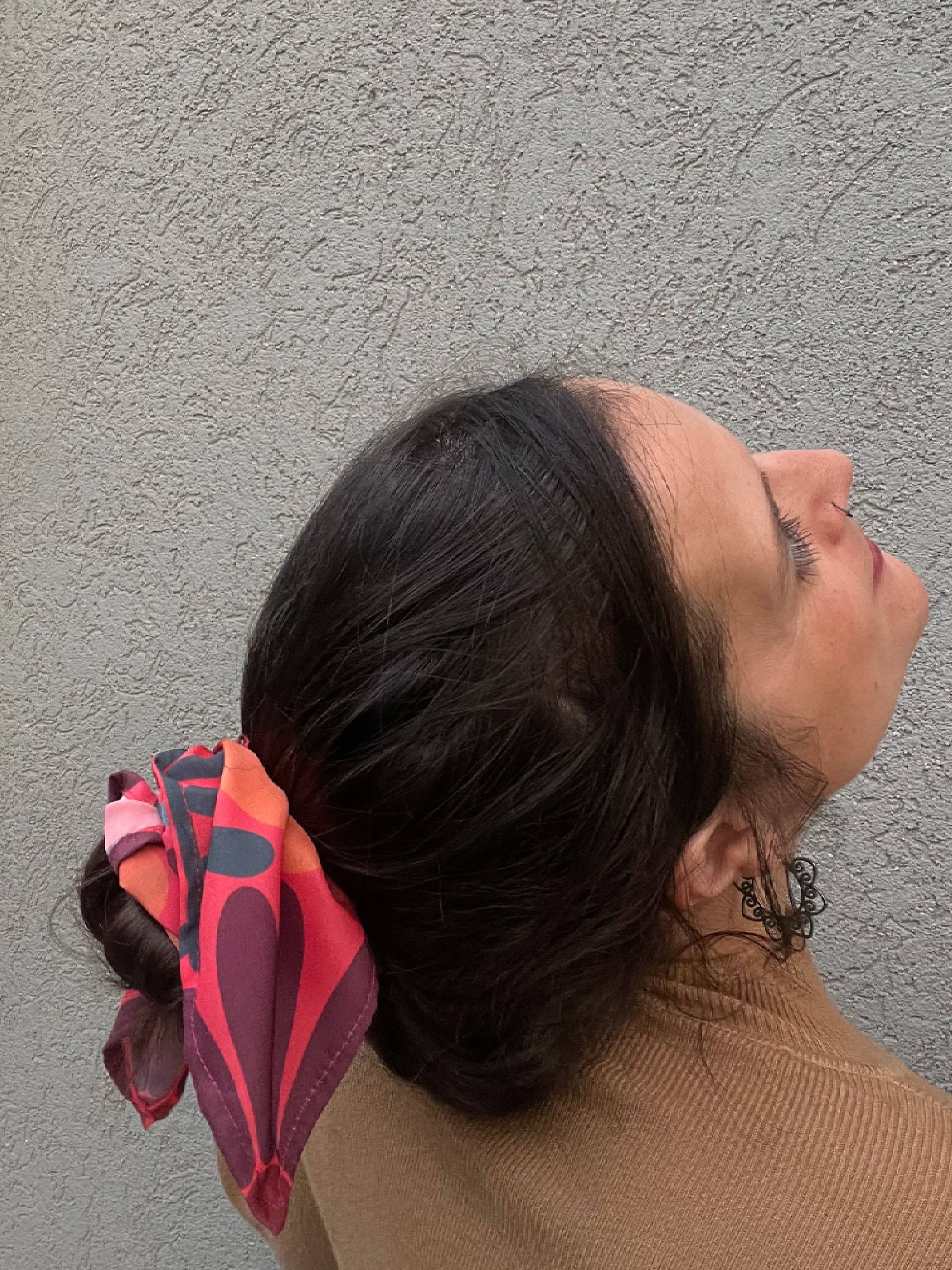 Bufanda roja con formas abstractas y lunares, dispuestos en forma circular sobre una superficie blanca.