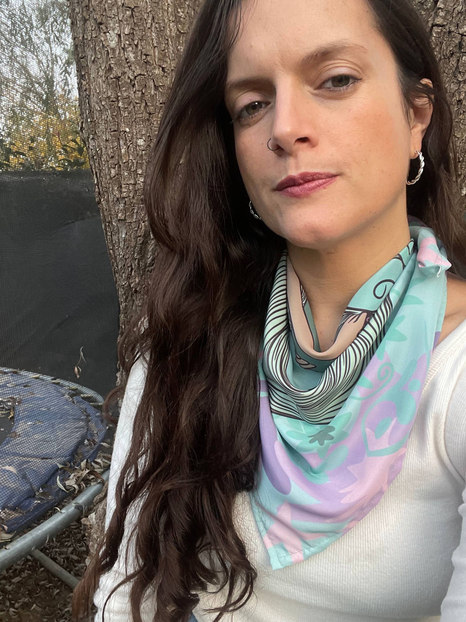 Bufanda circular con estampado floral y de rostro de mujer en tonos azules, morados y rosas.