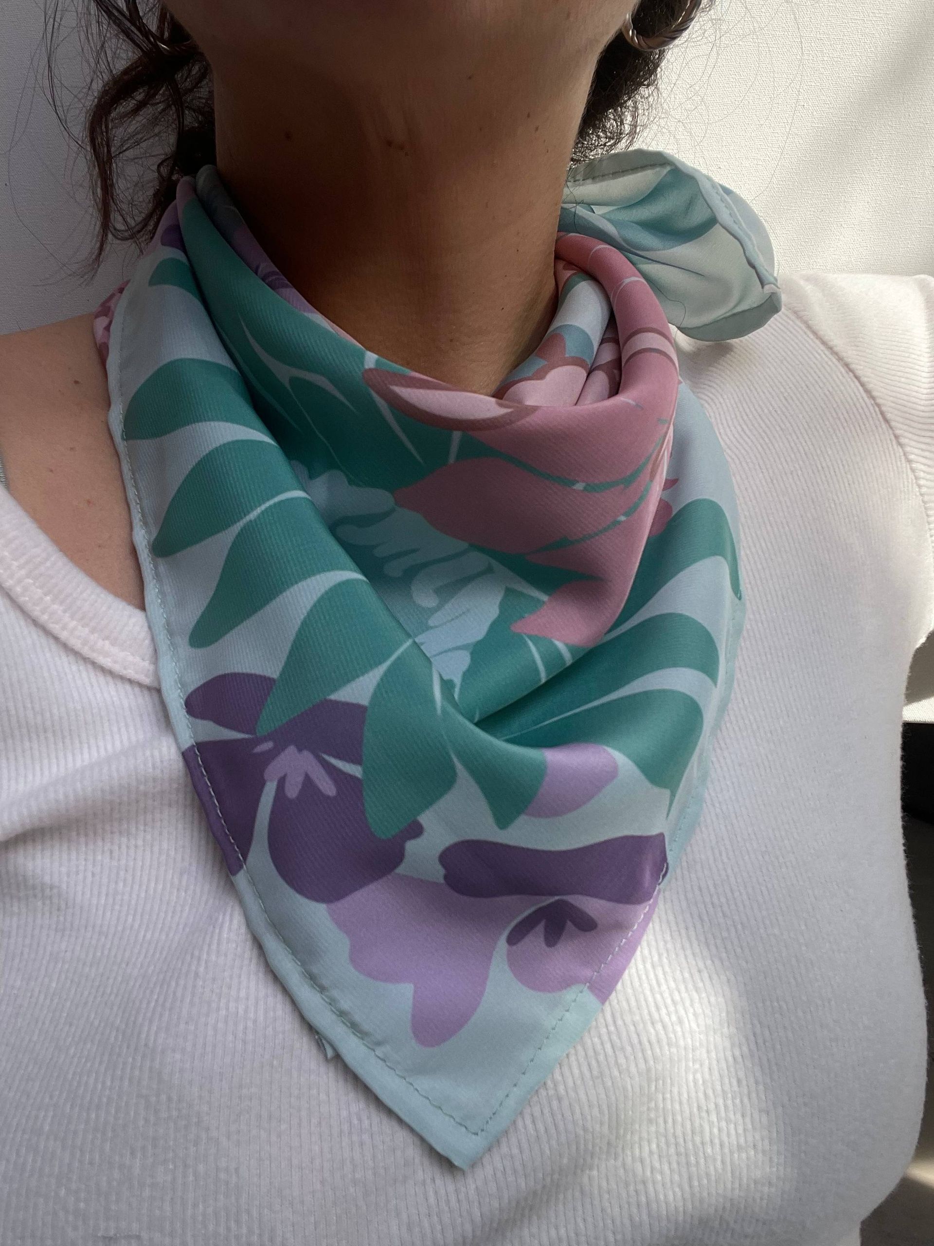 Bufanda infinita con estampado floral en tonos rosas, verdes y morados, sobre una superficie blanca.