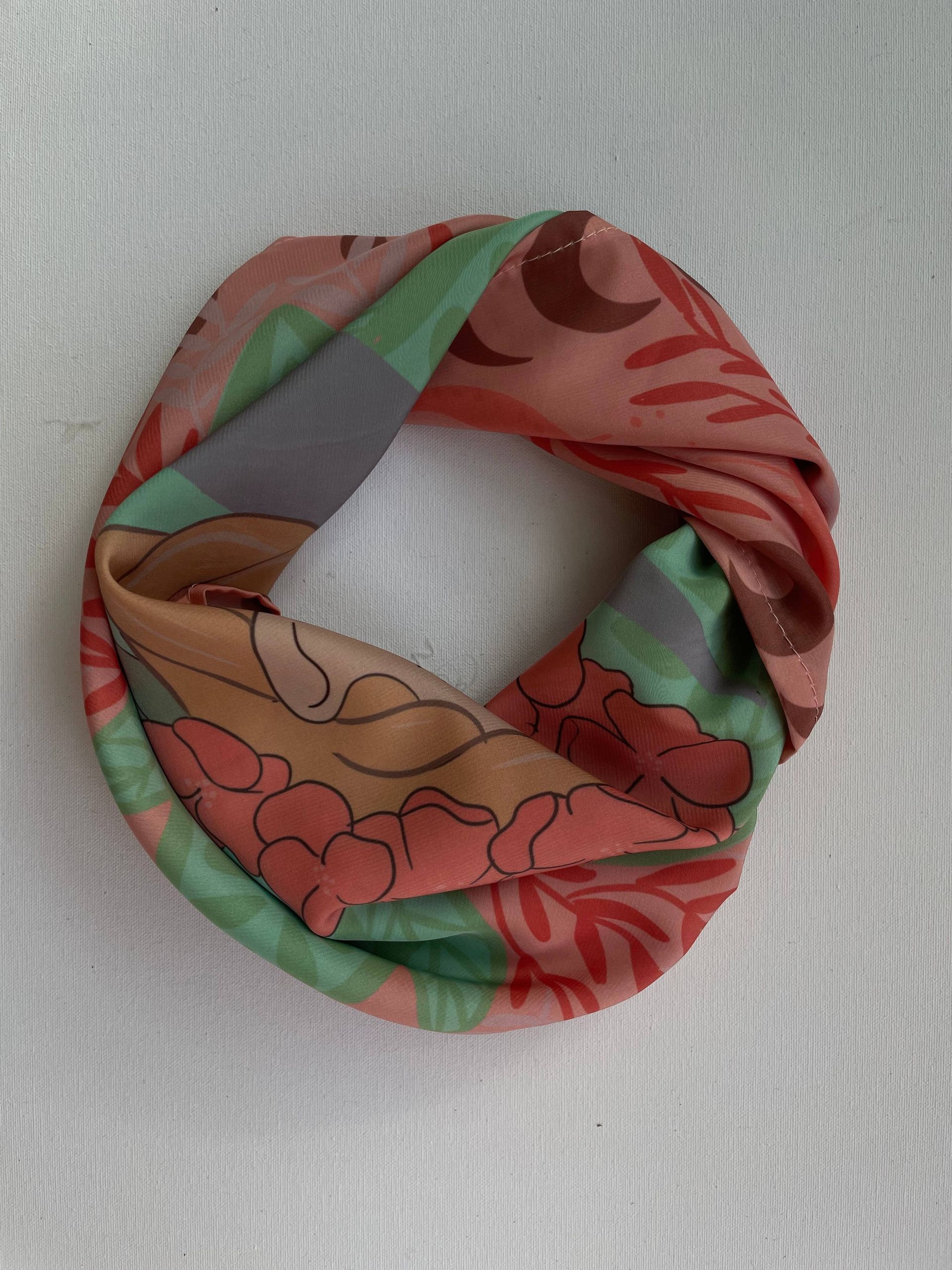 Una bufanda con estampado floral reposa sobre una superficie blanca.