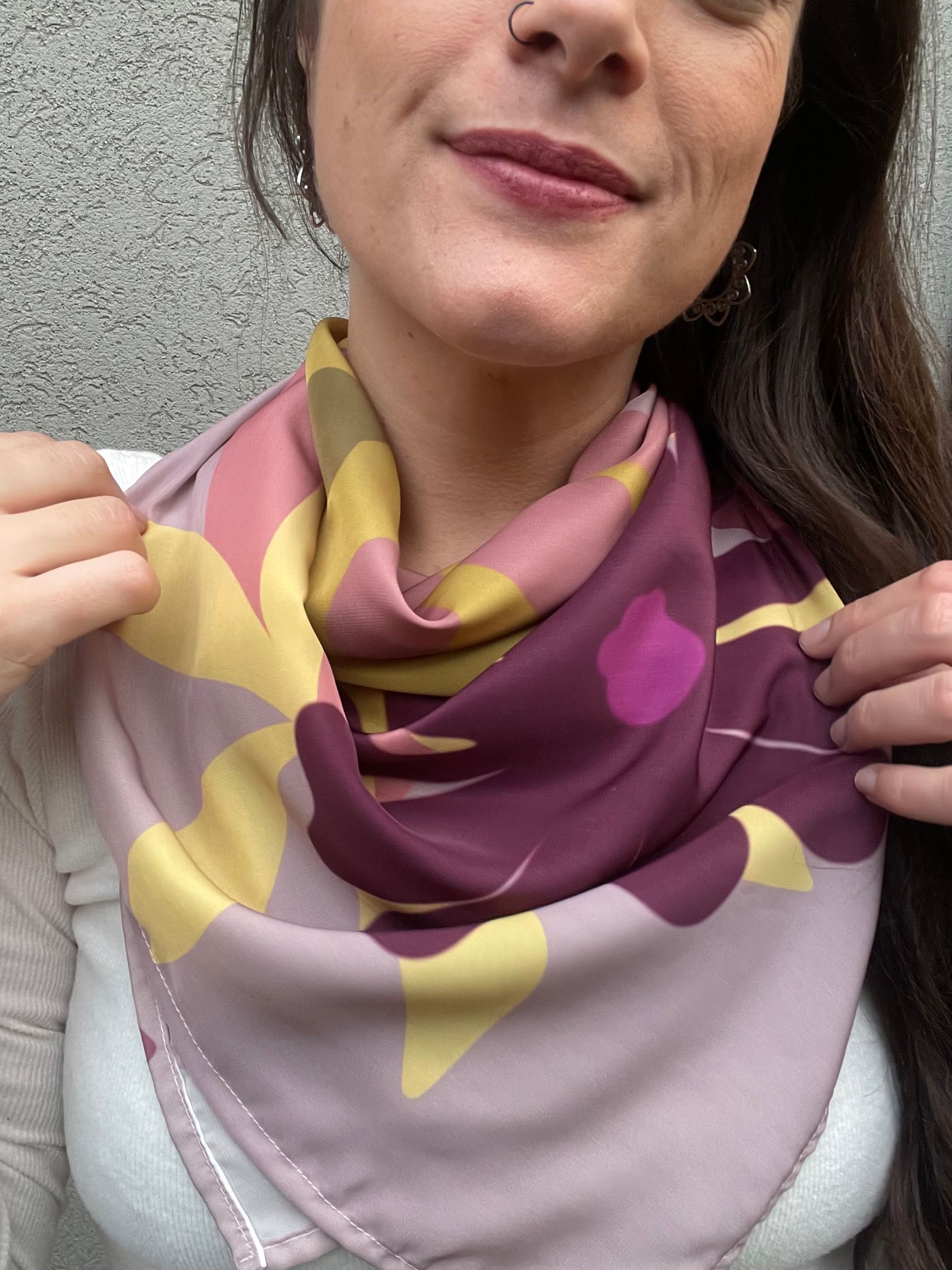 Mujer que lleva un pañuelo de seda colorido, sonriendo; sobre un fondo gris.