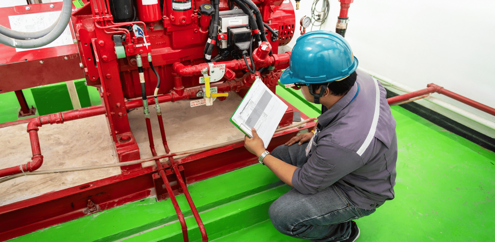 Un homme est agenouillé devant une machine et lit un livre.