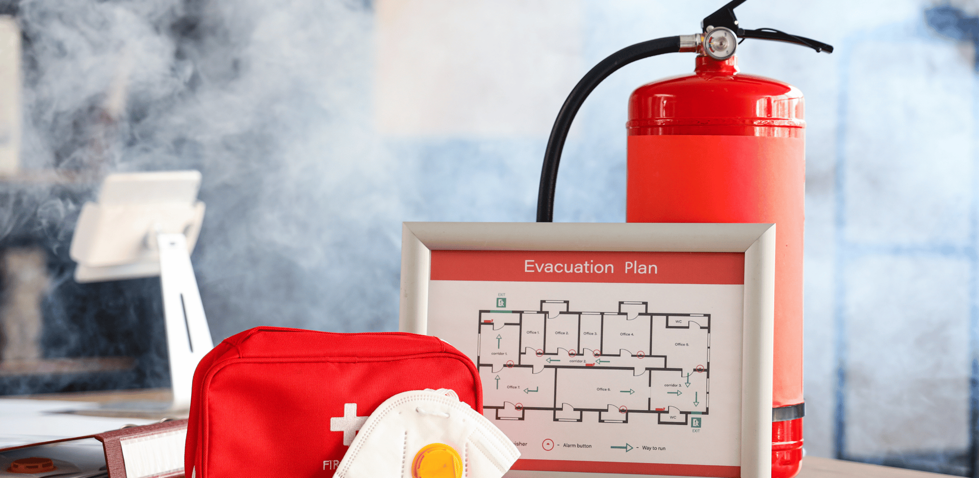 Un extincteur est posé sur un bureau à côté d'une trousse de premiers secours.