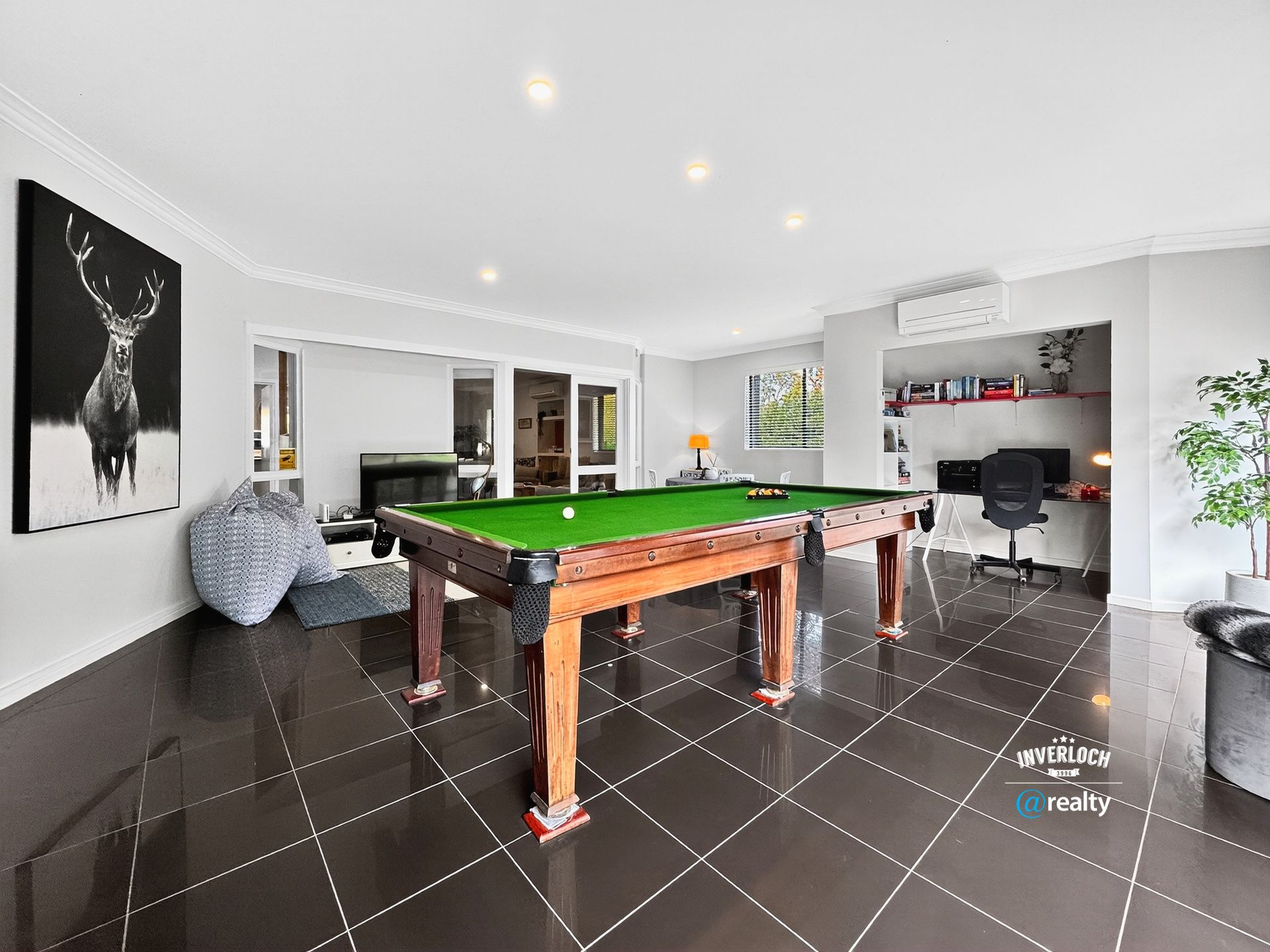 Pool table in a spacious room with glossy tile floors, fireplace, and office area.