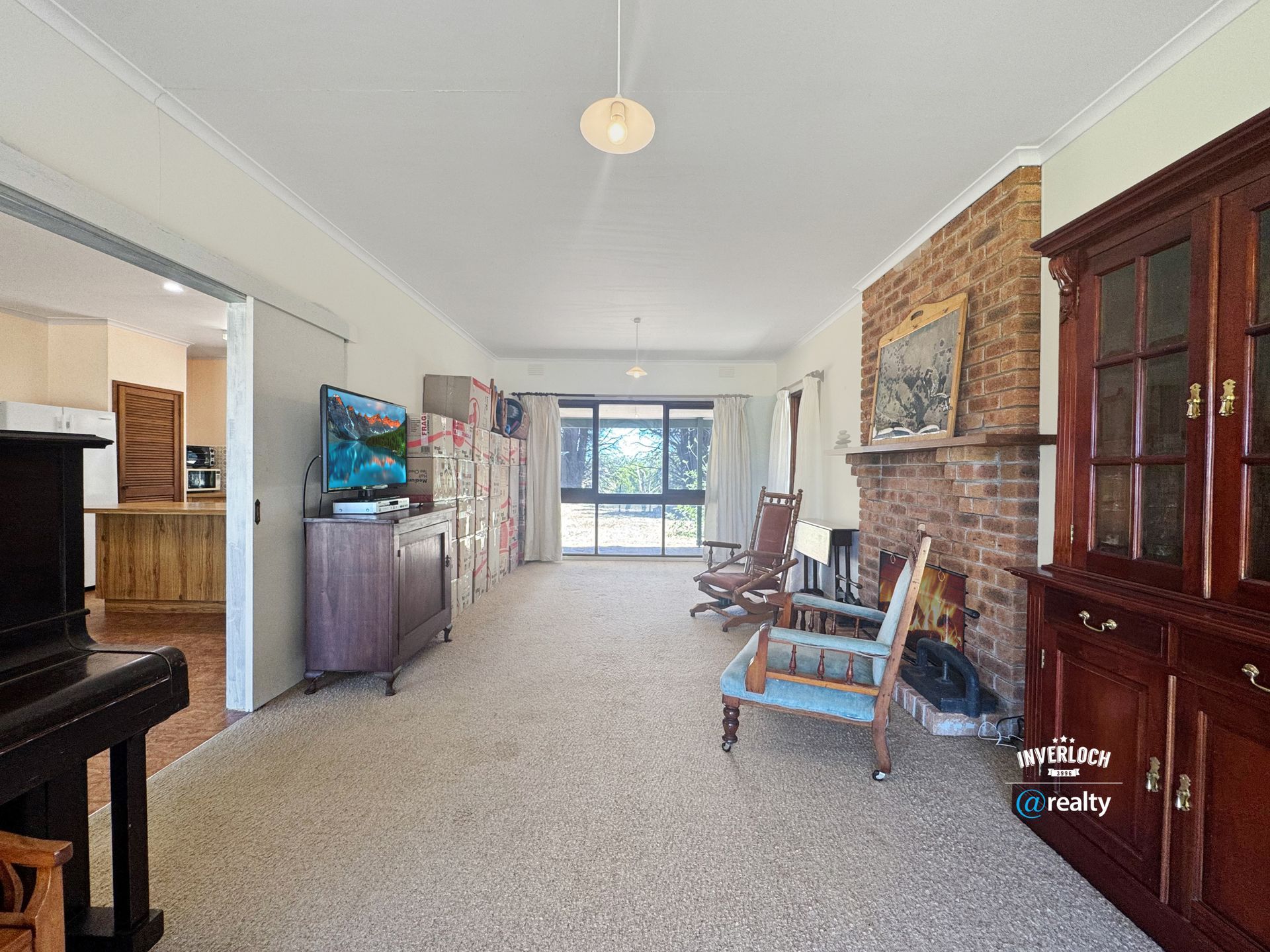 Long living room with a brick fireplace, built-in cabinets, and a piano.