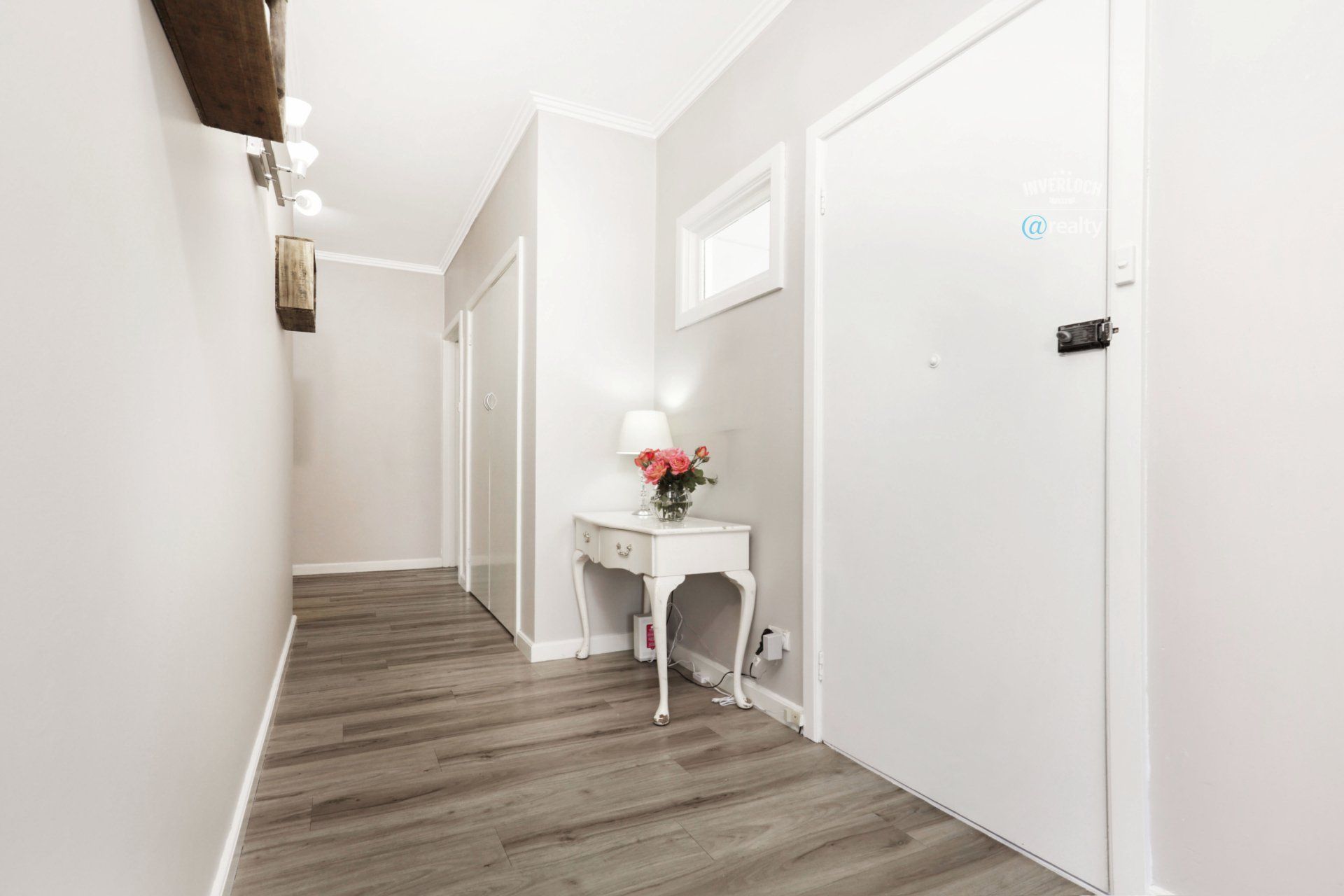 A long hallway with a table and a vase of flowers on it.