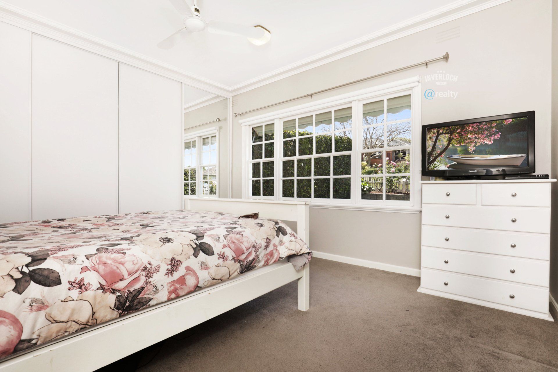 A bedroom with a bed , dresser , and television.