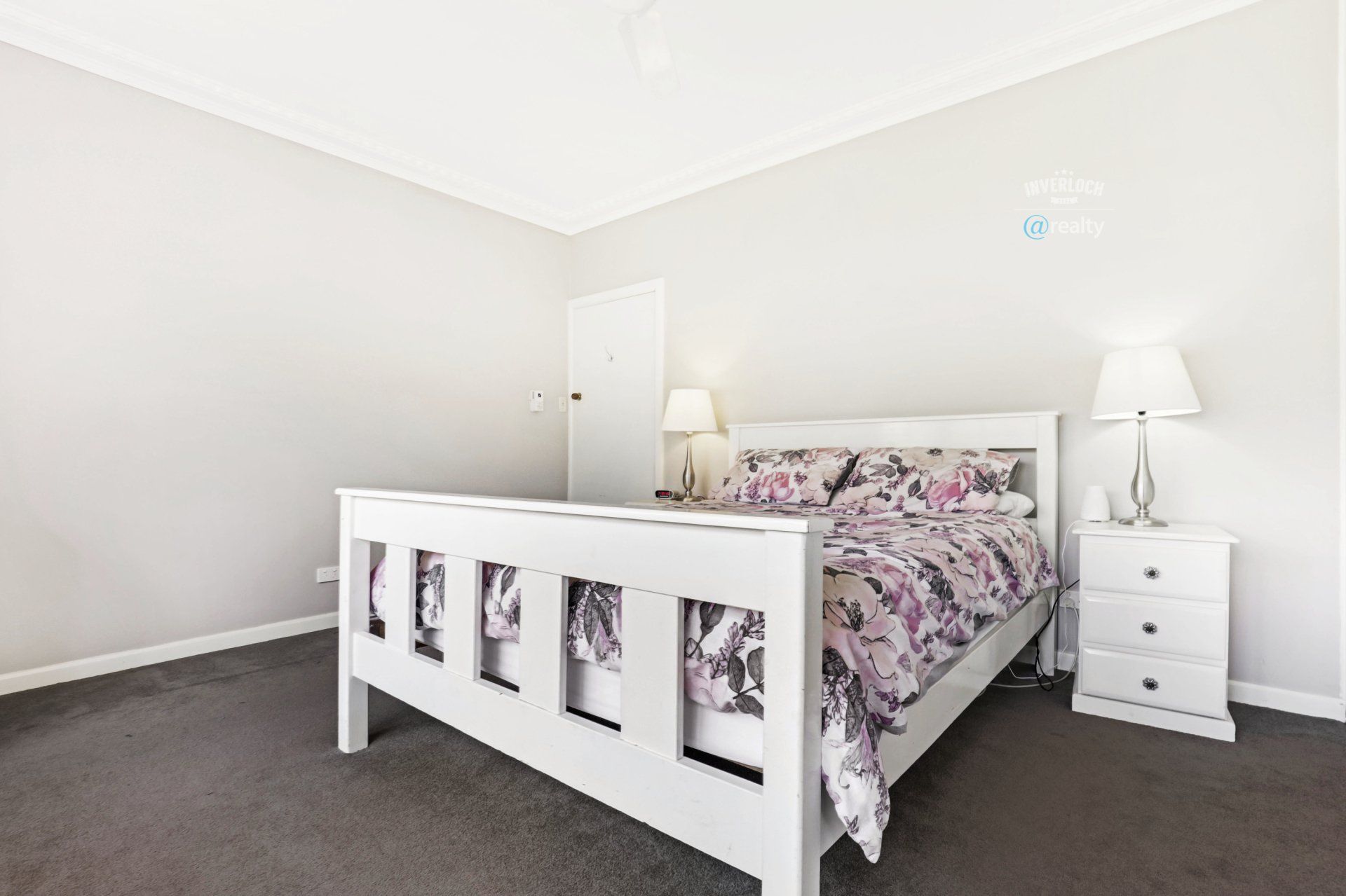 A bedroom with a bed , nightstand , and lamps.