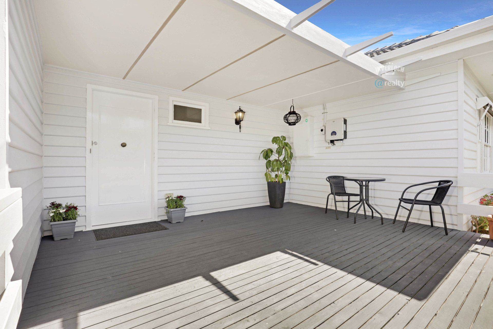 A white house with a covered porch with a table and chairs.