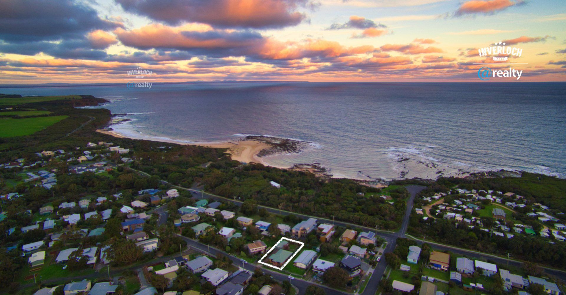 An aerial view of a residential area next to the ocean at sunset.