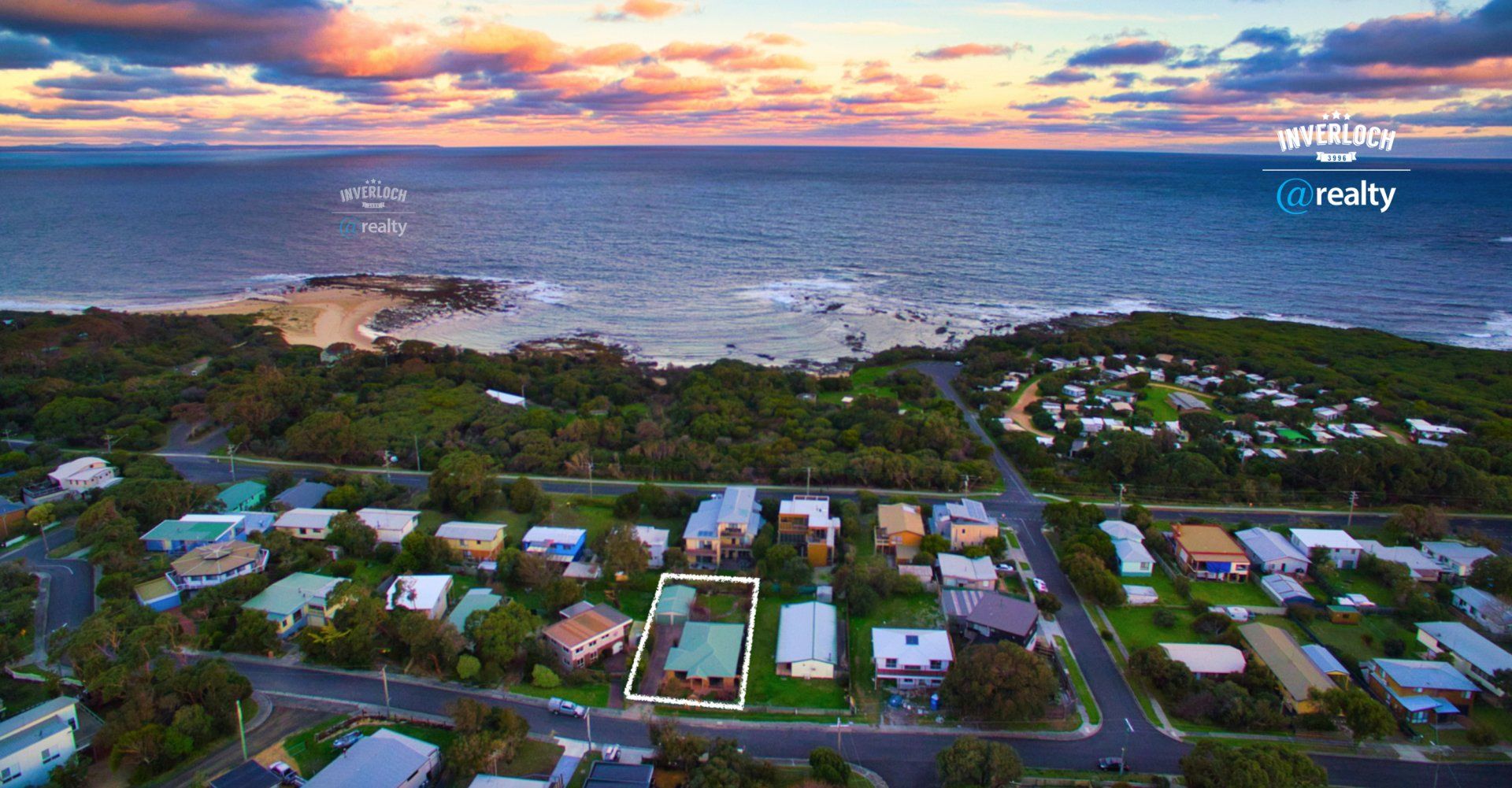 An aerial view of a residential area next to the ocean at sunset.