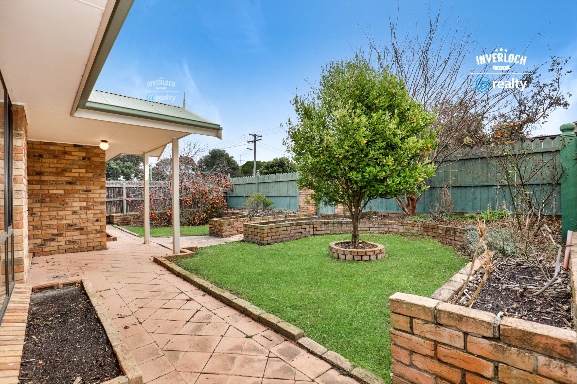 A brick house with a large lawn and a tree in the backyard.