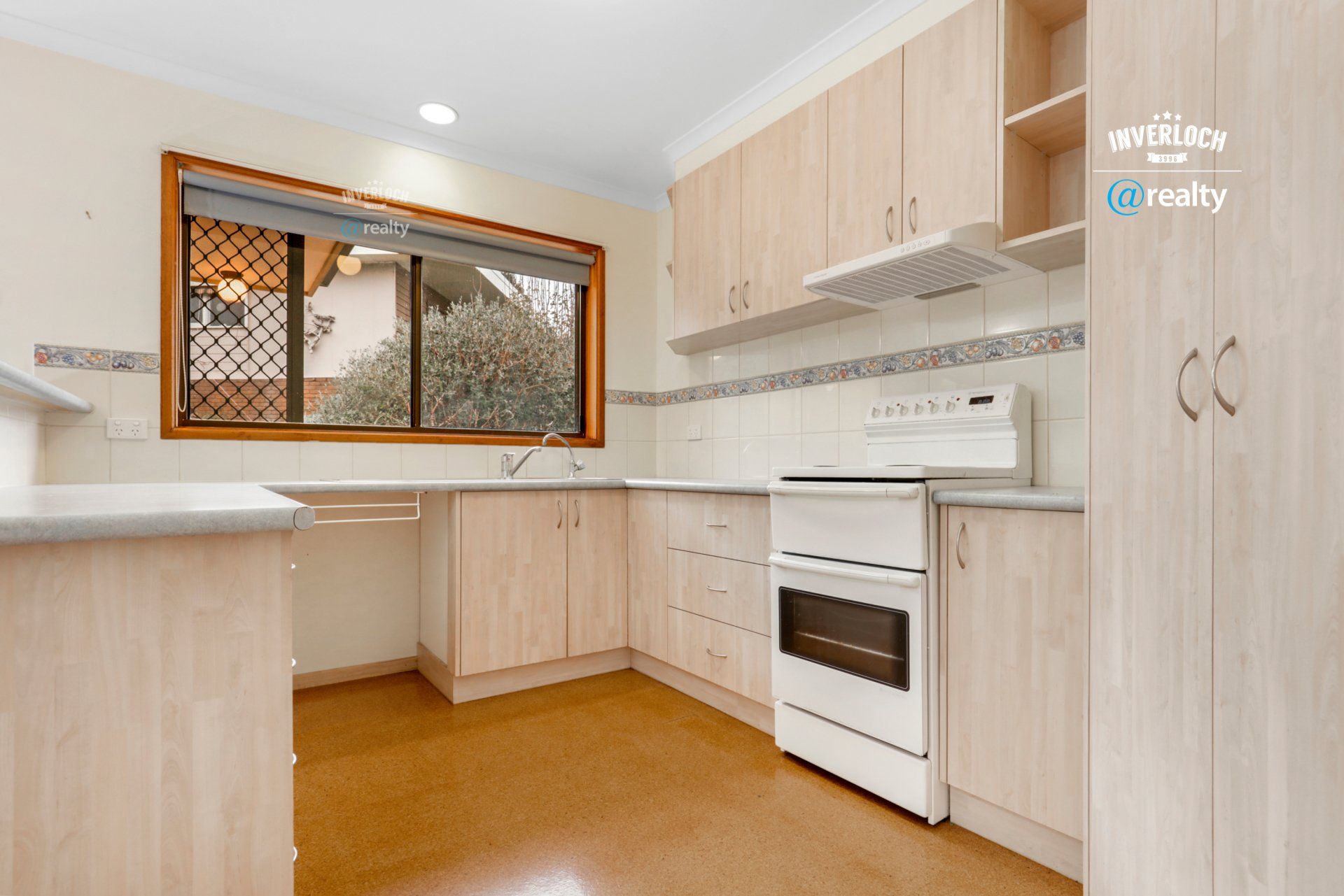 An empty kitchen with wooden cabinets and a white stove.