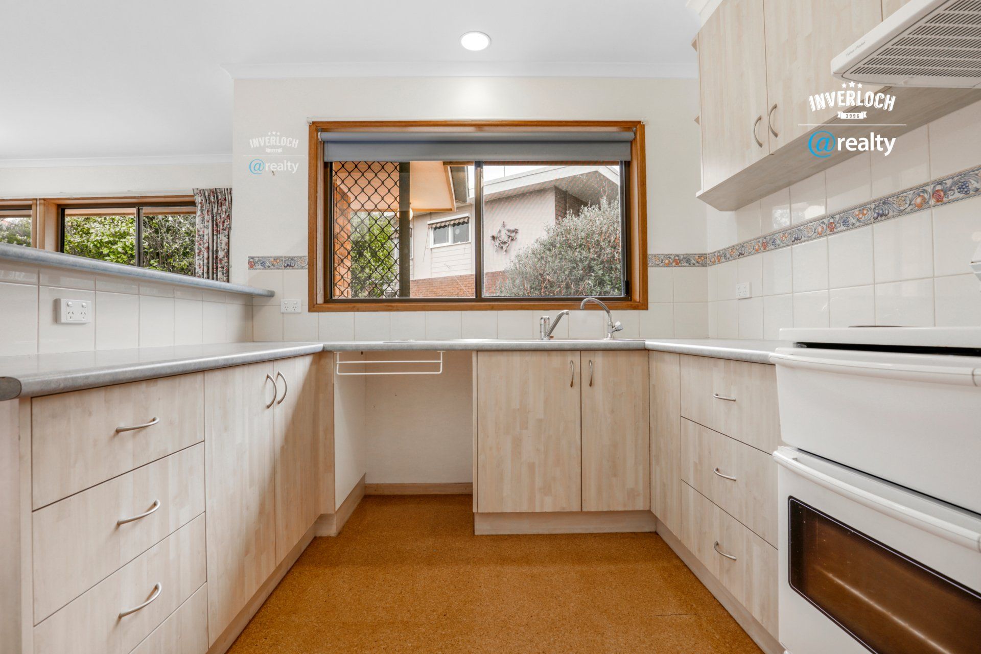 An empty kitchen with wooden cabinets and a window.