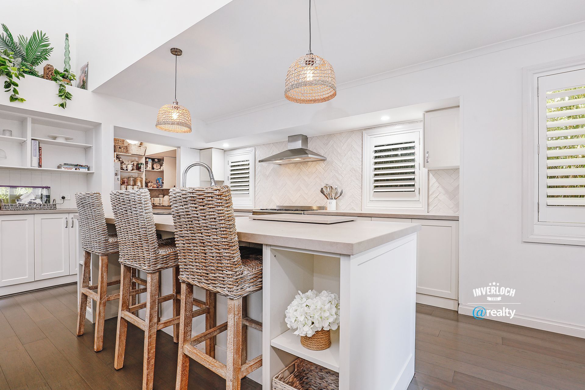 A kitchen with a large island and wicker chairs.