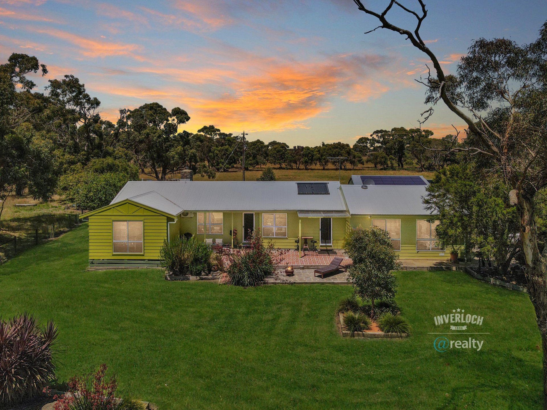 A yellow house sits in the middle of a lush green field