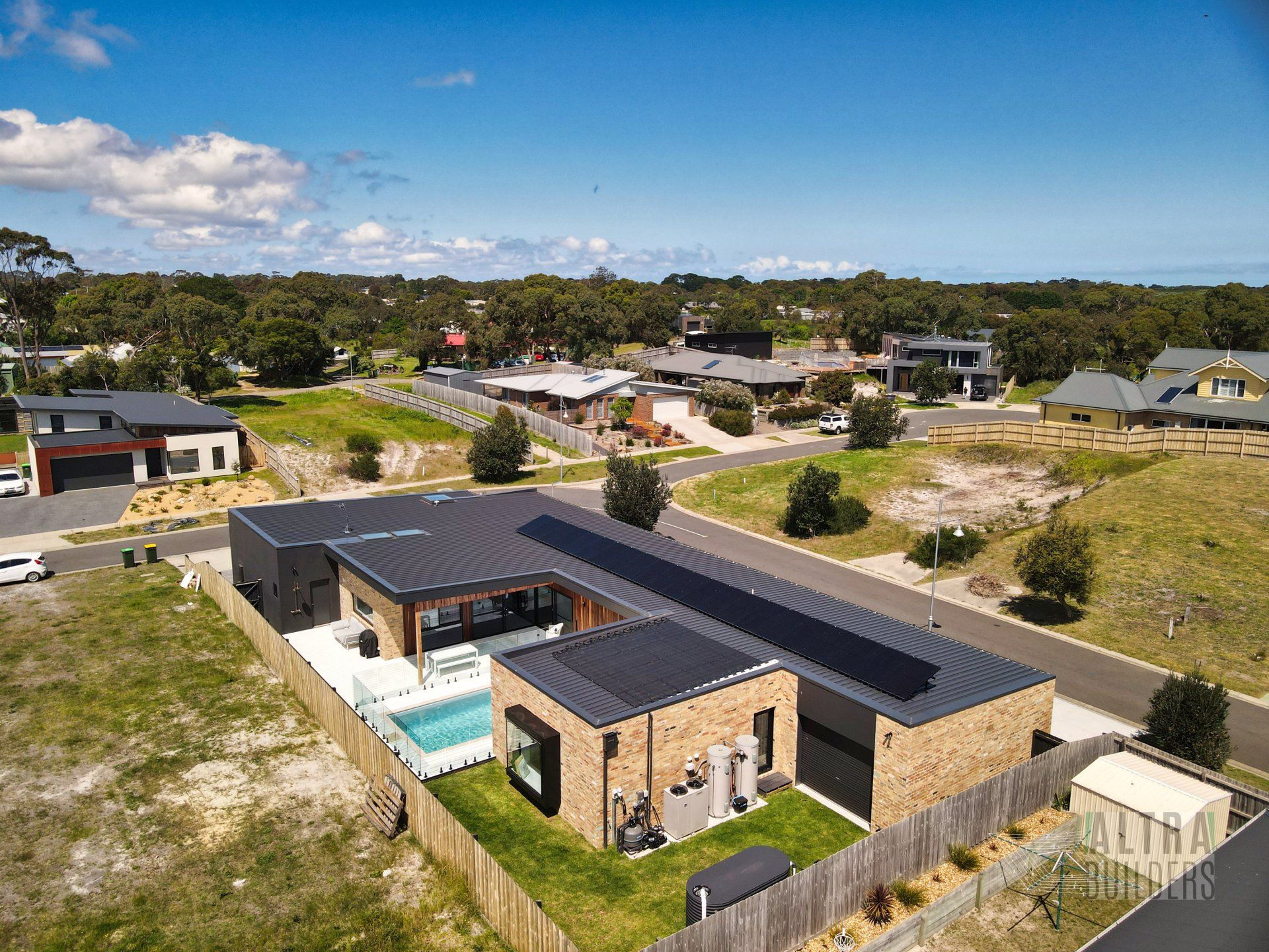 An aerial view of a house with a pool in a residential area.