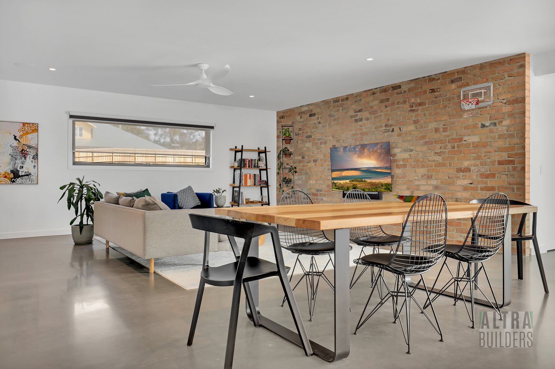 A living room with a dining table and chairs and a brick wall.