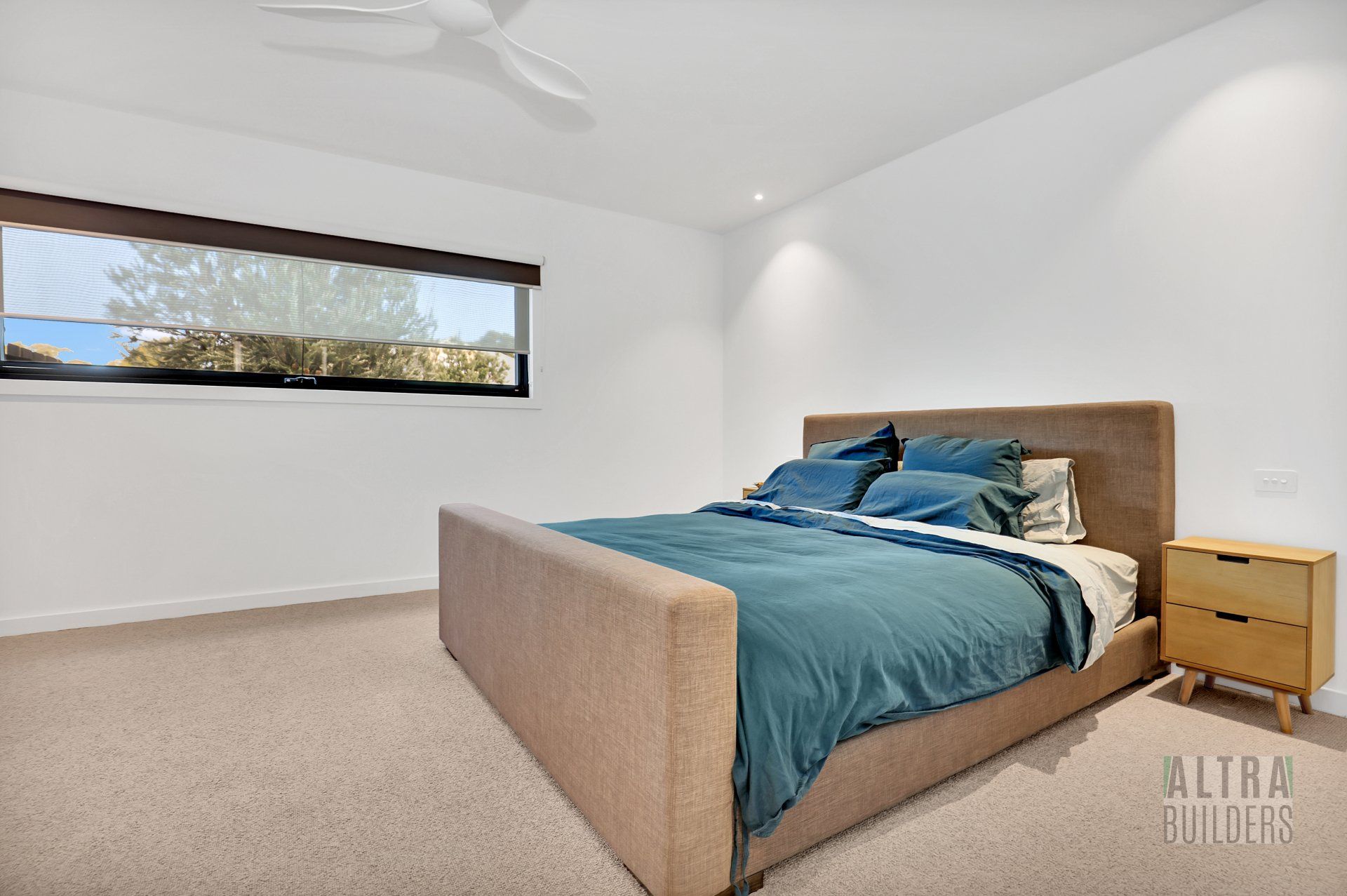 A bedroom with a large bed , nightstand , and ceiling fan.