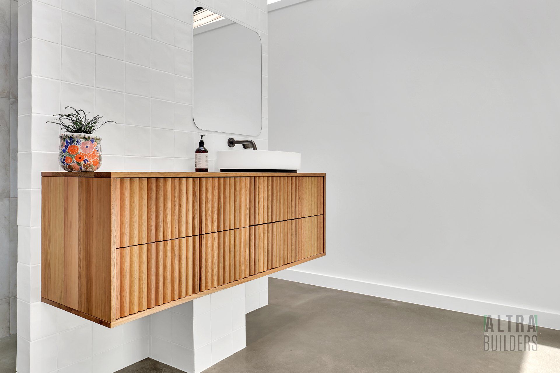 A bathroom with a wooden vanity , sink and mirror.