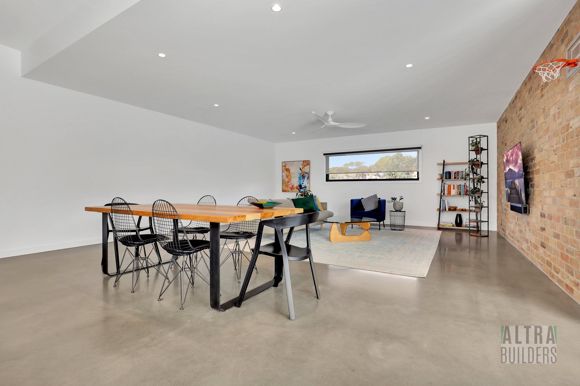 A living room with a table and chairs and a television on the wall.