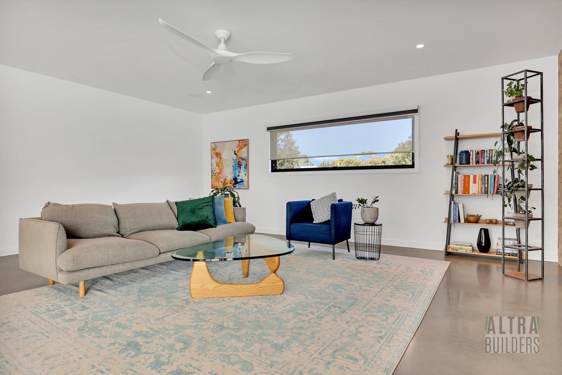 A living room with a couch , chair , coffee table and ceiling fan.