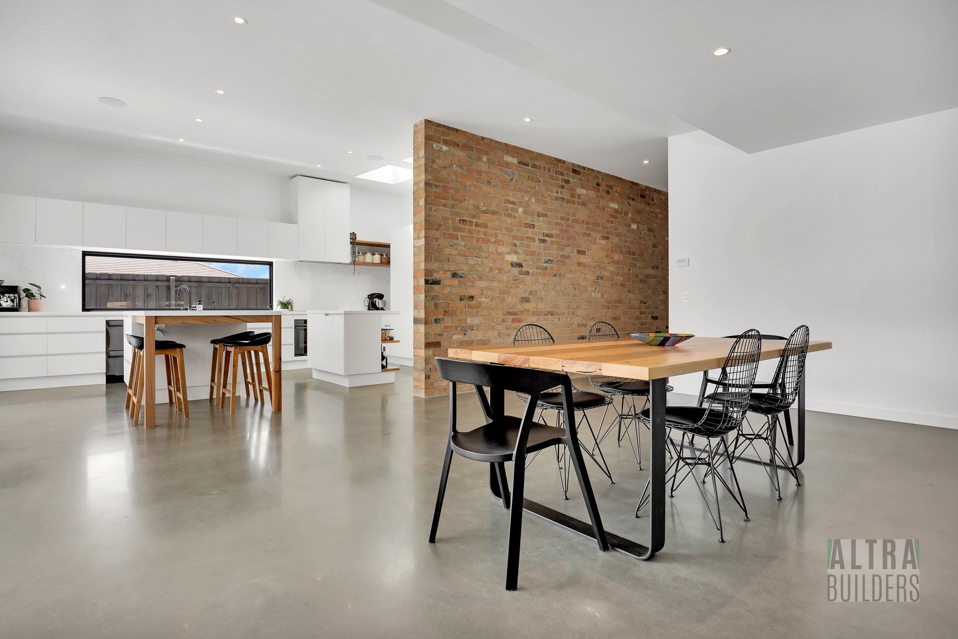 A dining table and chairs in a kitchen with a brick wall