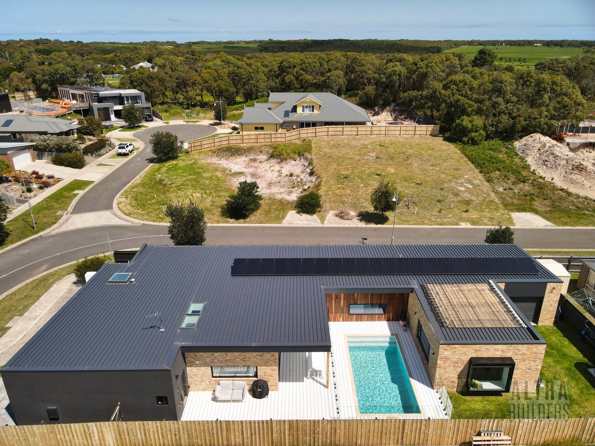 An aerial view of a house with a swimming pool in a residential area.