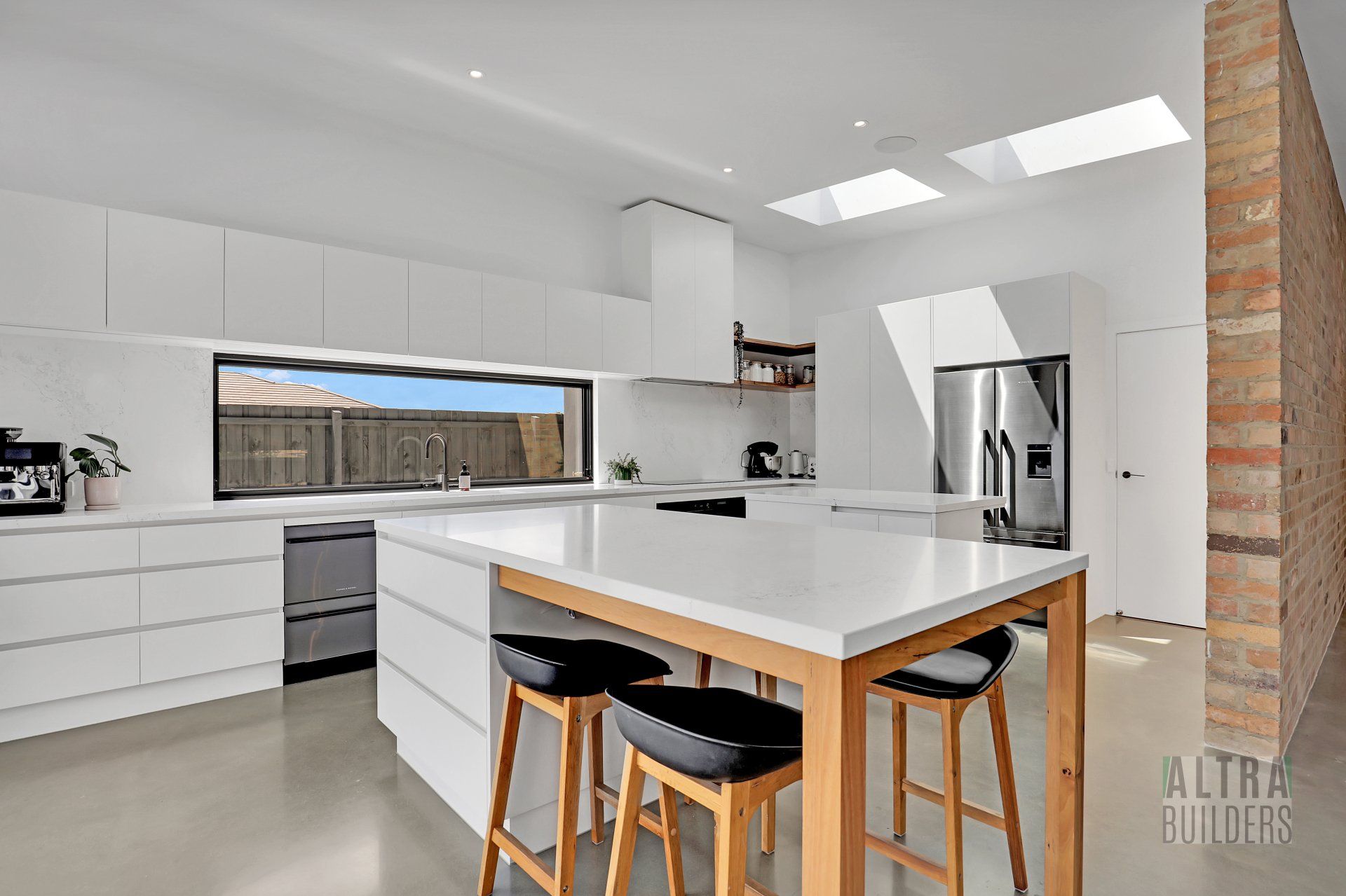 A kitchen with white cabinets and stools and a large island