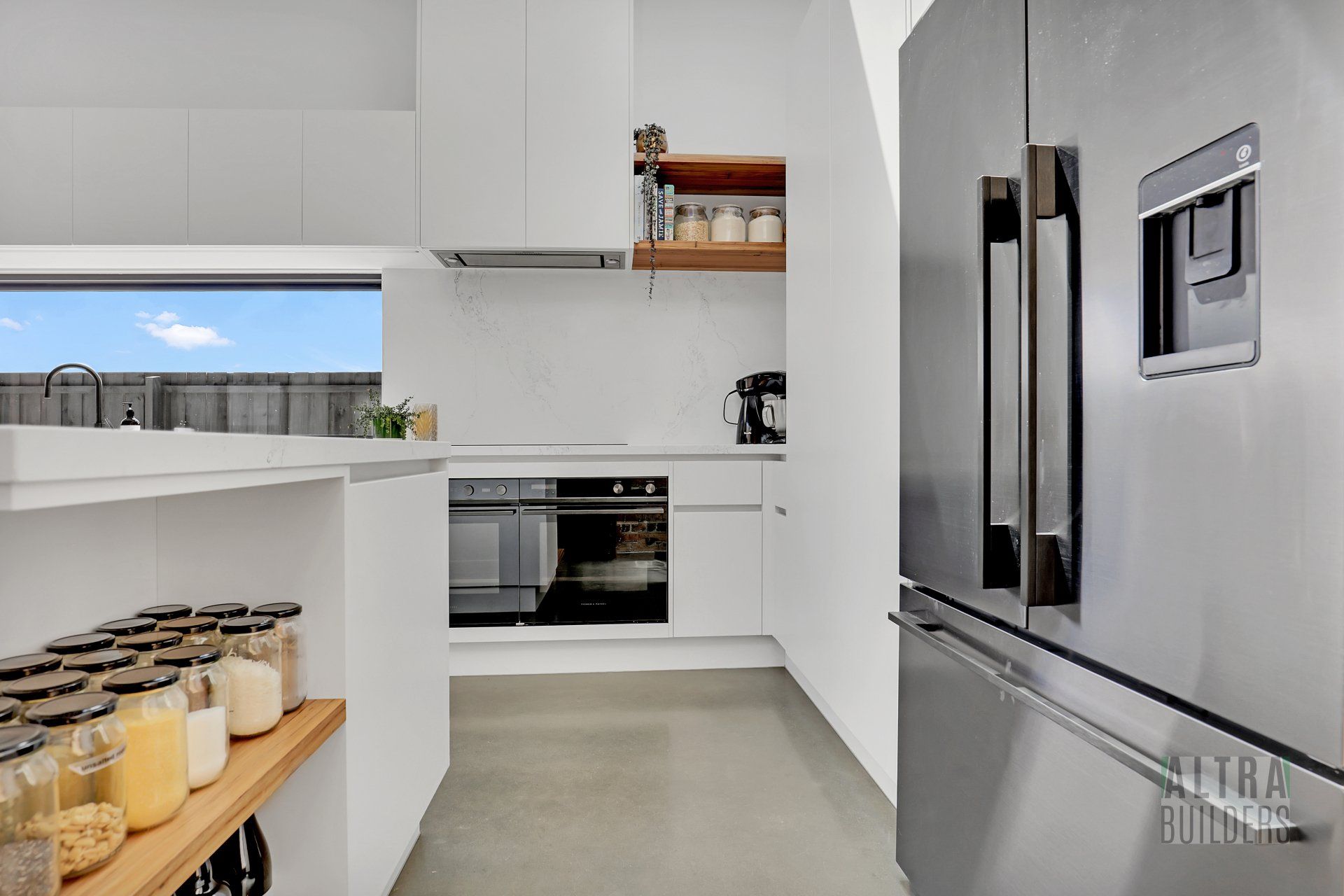 A kitchen with white cabinets and a stainless steel refrigerator