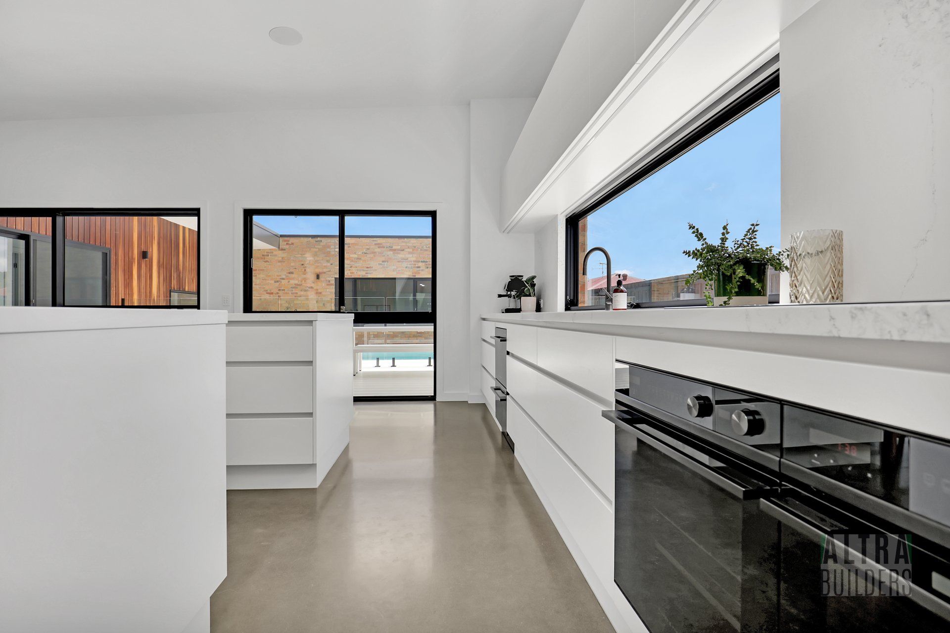 A kitchen with white cabinets and black appliances and a large window.