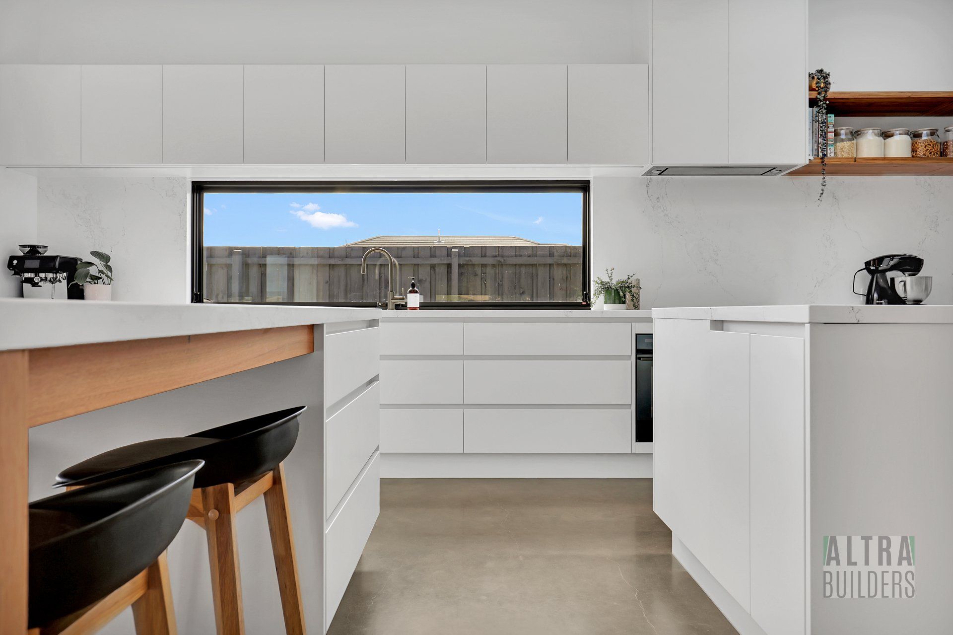 A kitchen with white cabinets and a large window