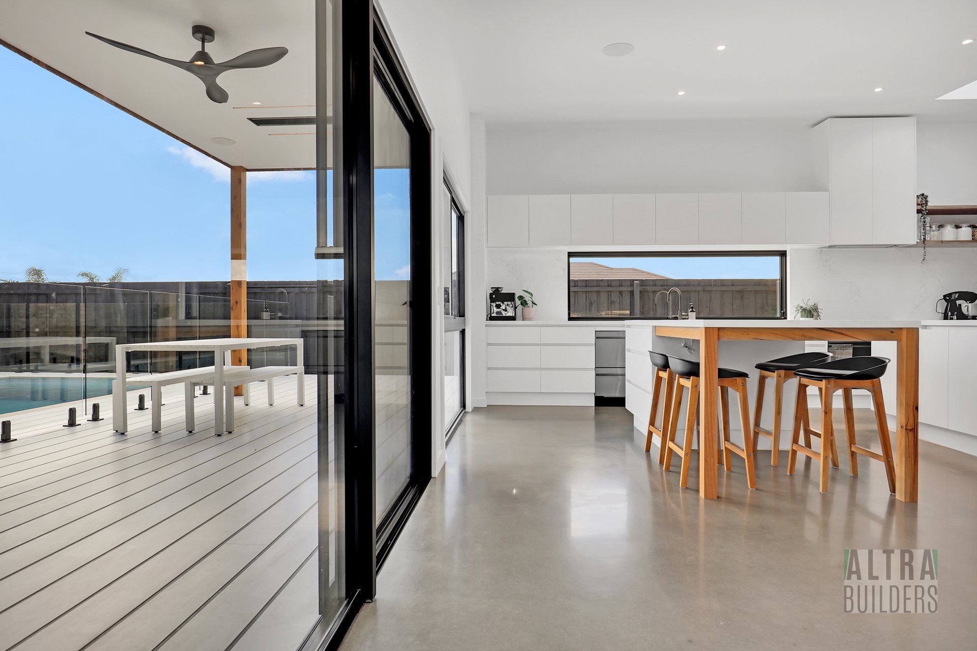 A kitchen with a table and stools and a ceiling fan