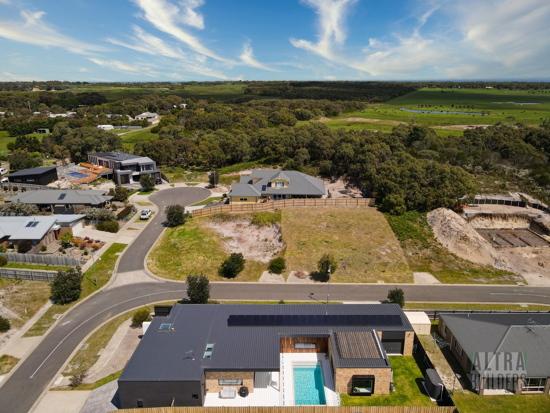 An aerial view of a house with a pool in the middle of a residential area.