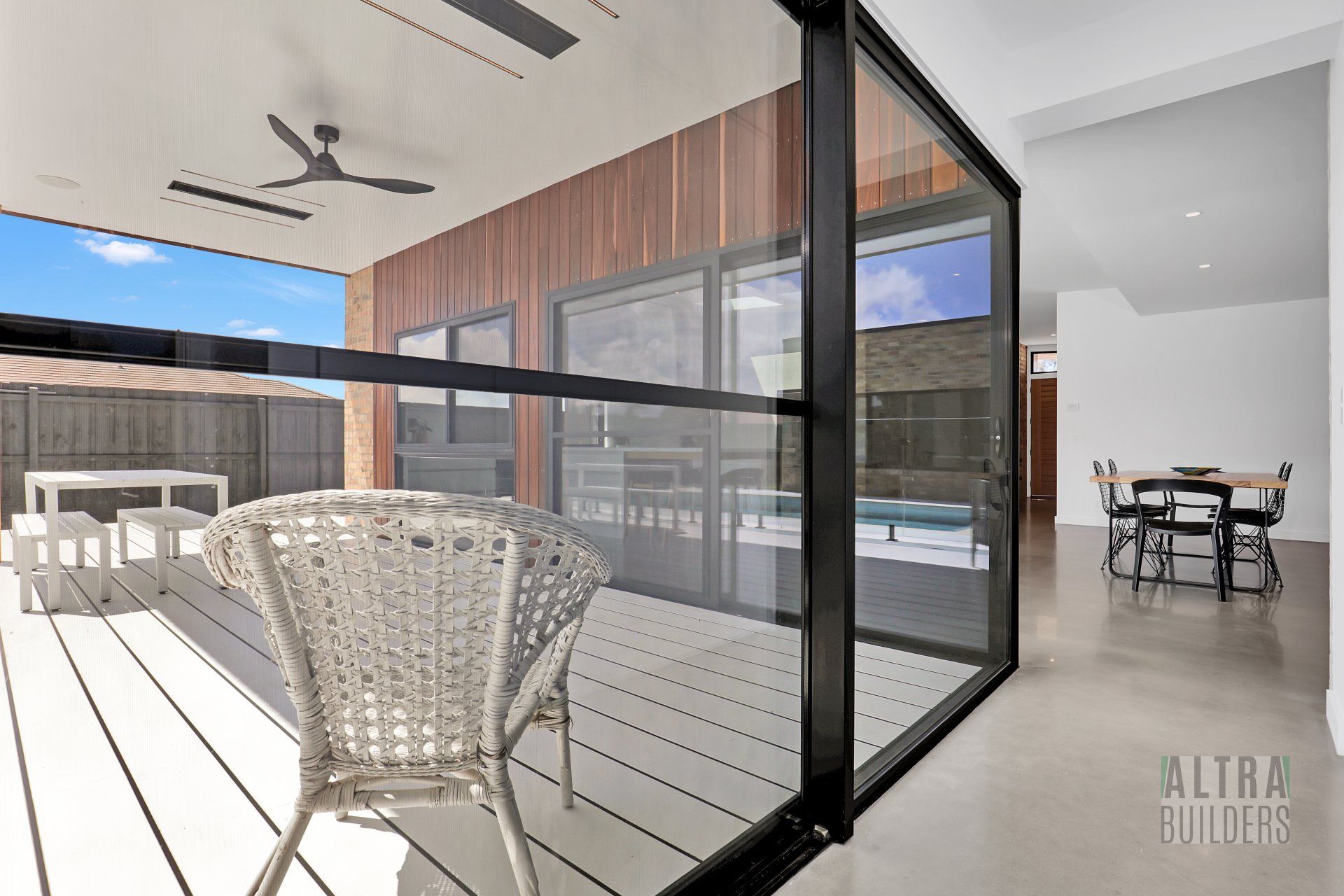 A wicker chair is sitting on a deck in front of a glass wall.