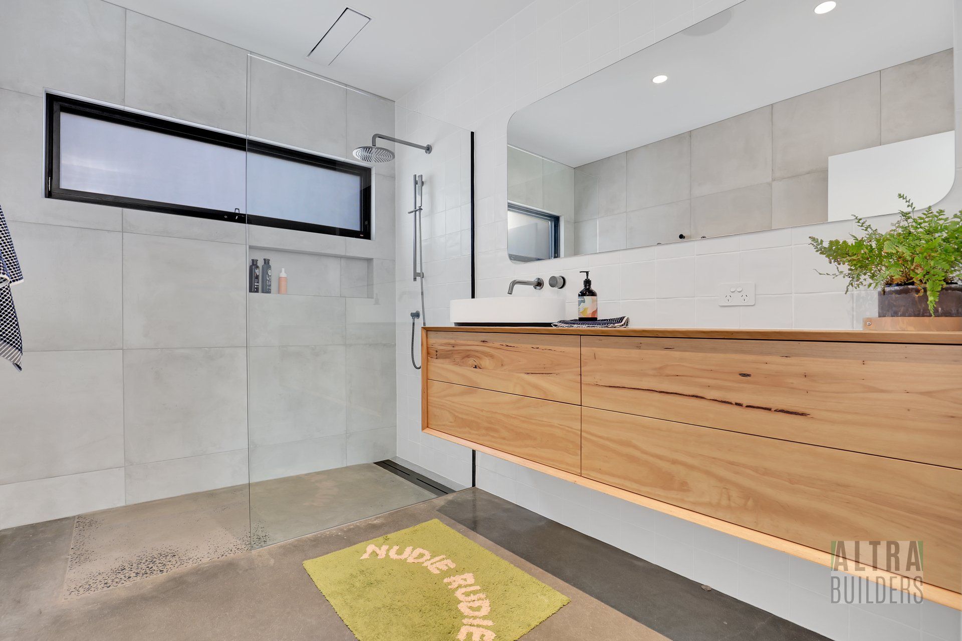 A bathroom with a sink , mirror and walk in shower.