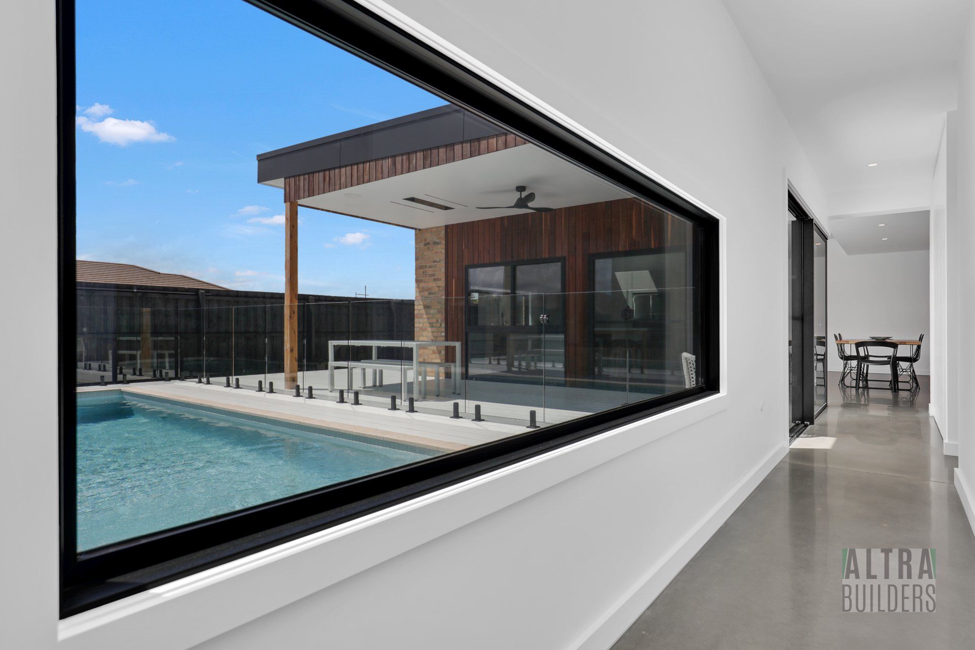 A large window with a view of a swimming pool in a house.