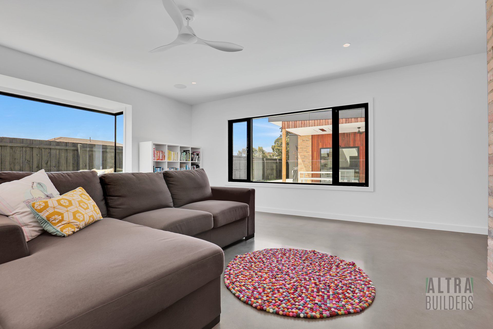 A living room with a couch , rug , window and ceiling fan.