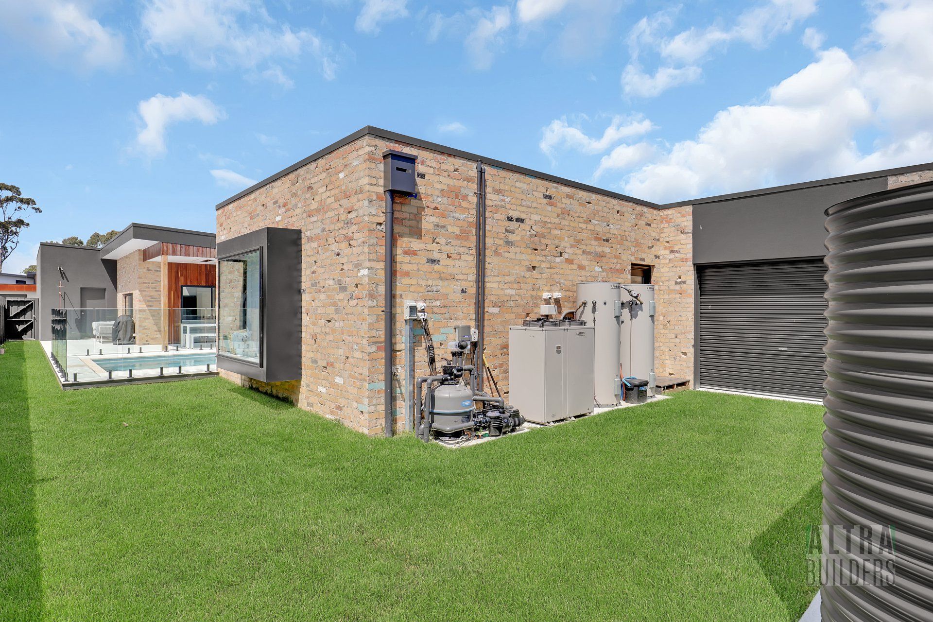 A brick house with a pool and a water tank in the backyard.