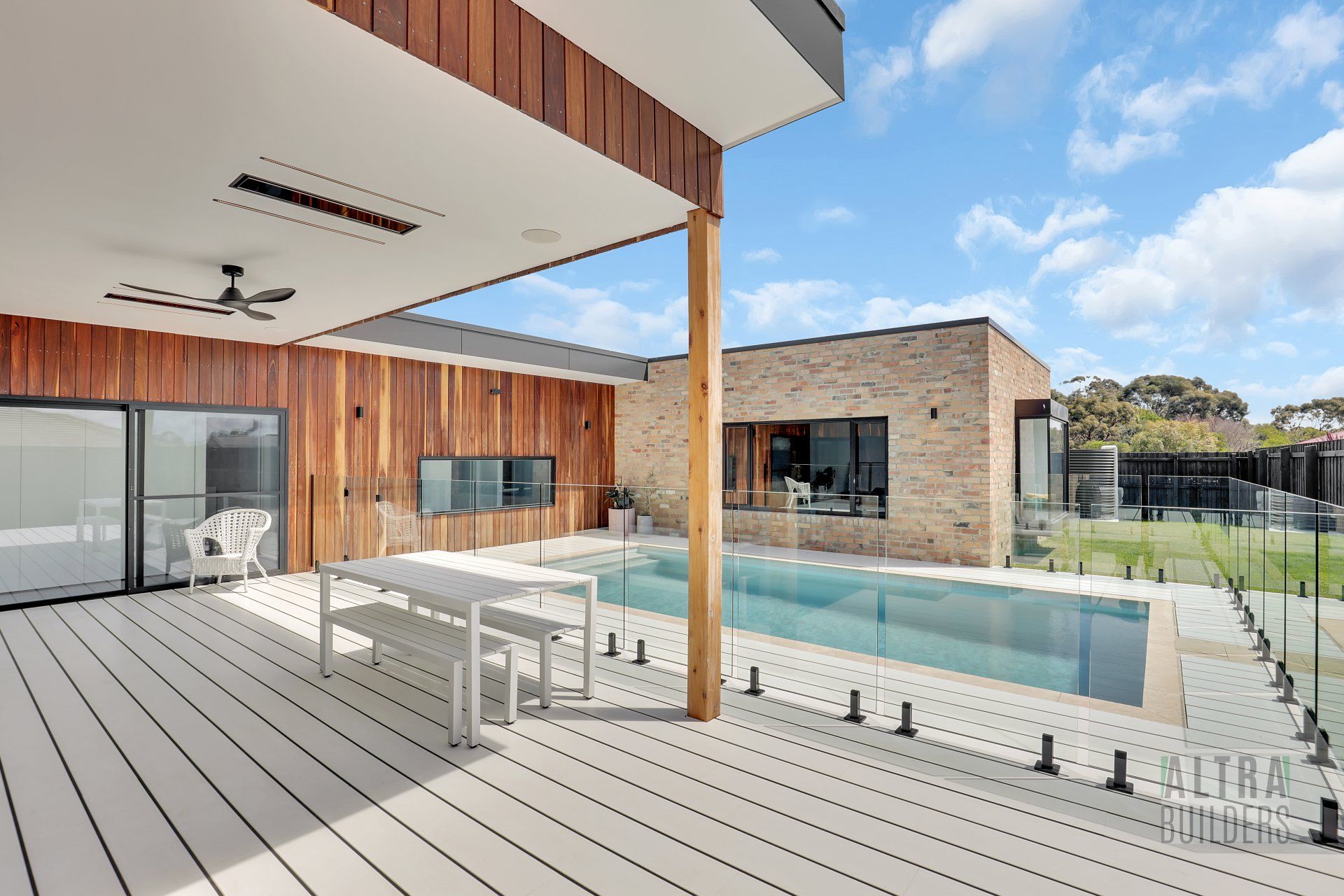 A deck with a table and chairs next to a swimming pool